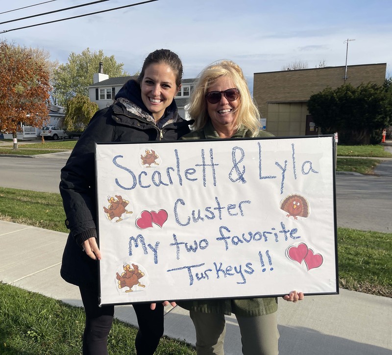 two family members hold sign cheering on their students