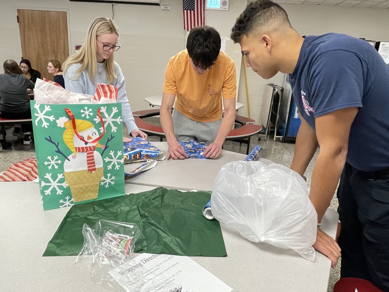 students wrap presents at a table