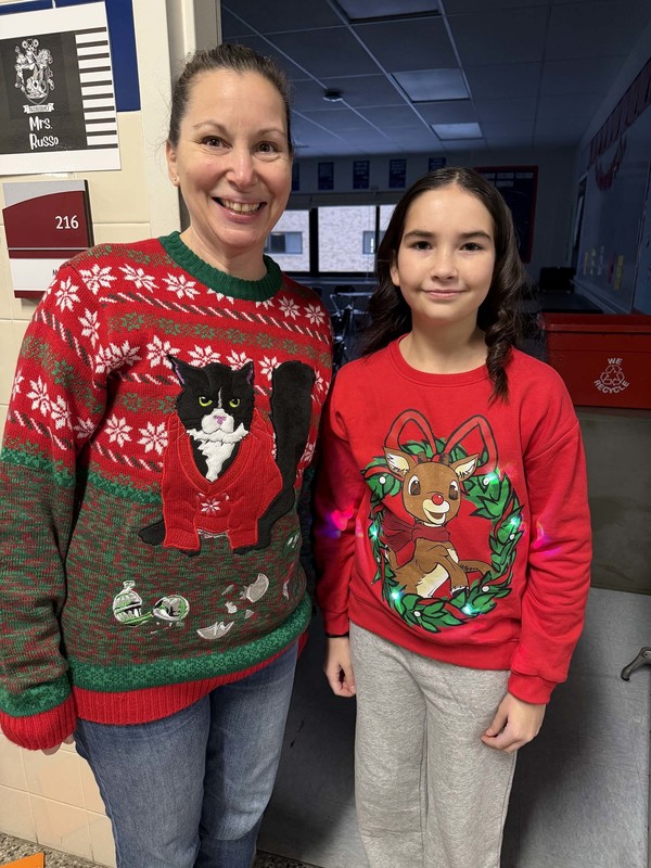 student and teacher pose in christmas sweaters
