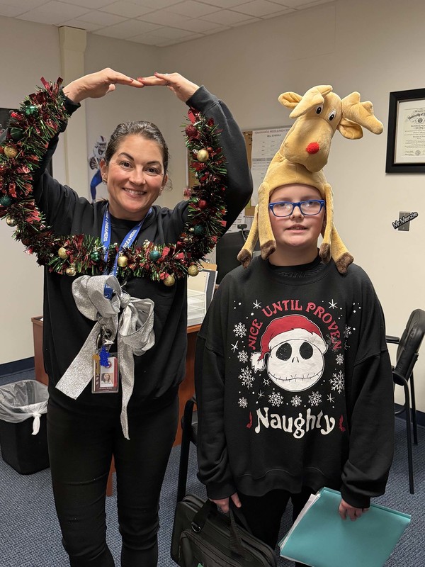 principal and student show off their christmas sweaters
