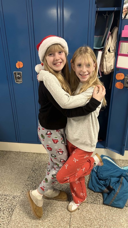 students pose in christmas jammies in front of open locker