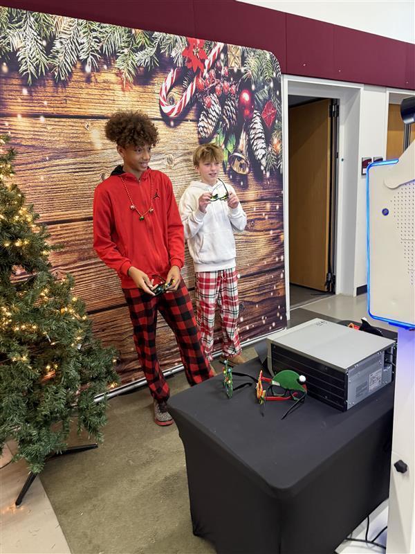 students stand in front of christmas scene wearing christmas jammies
