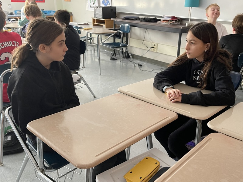 students sitting at desks staring at eachother