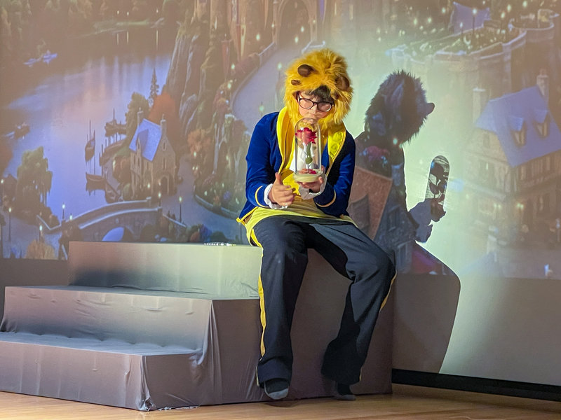 beast looks at rose inside the vase while sitting on steps