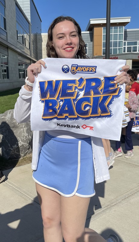 teacher holds up we're back towel and poses for camera