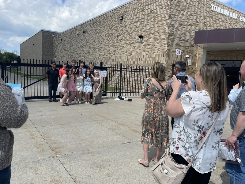 parents take photos as Students pose outside of football field