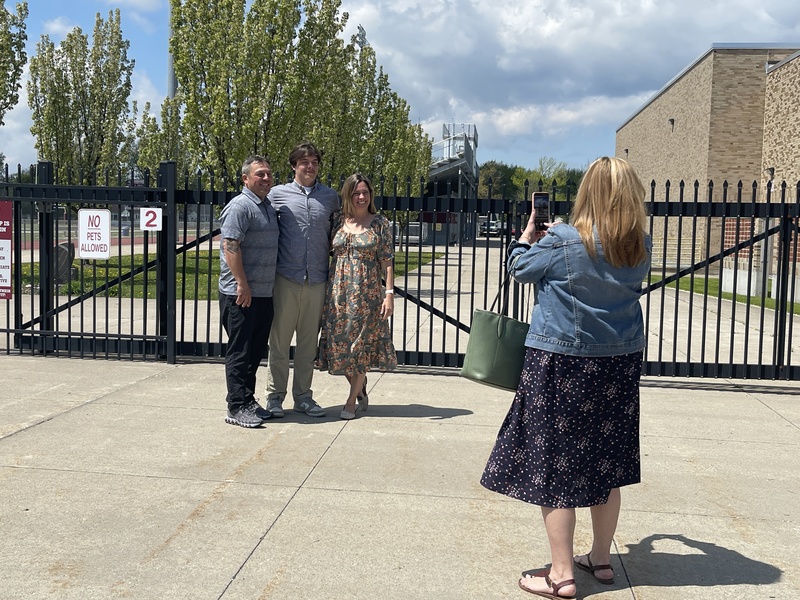 parents take photos as Students pose outside of football field