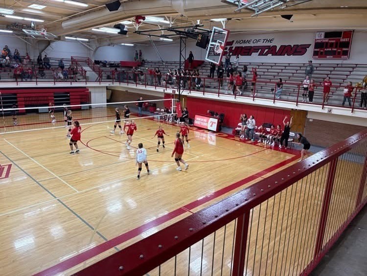seventh grade middle school girls playing volleyball in a high school gym
