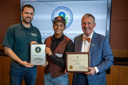 archer standing with EPA and parks dept staff, holding two plaques