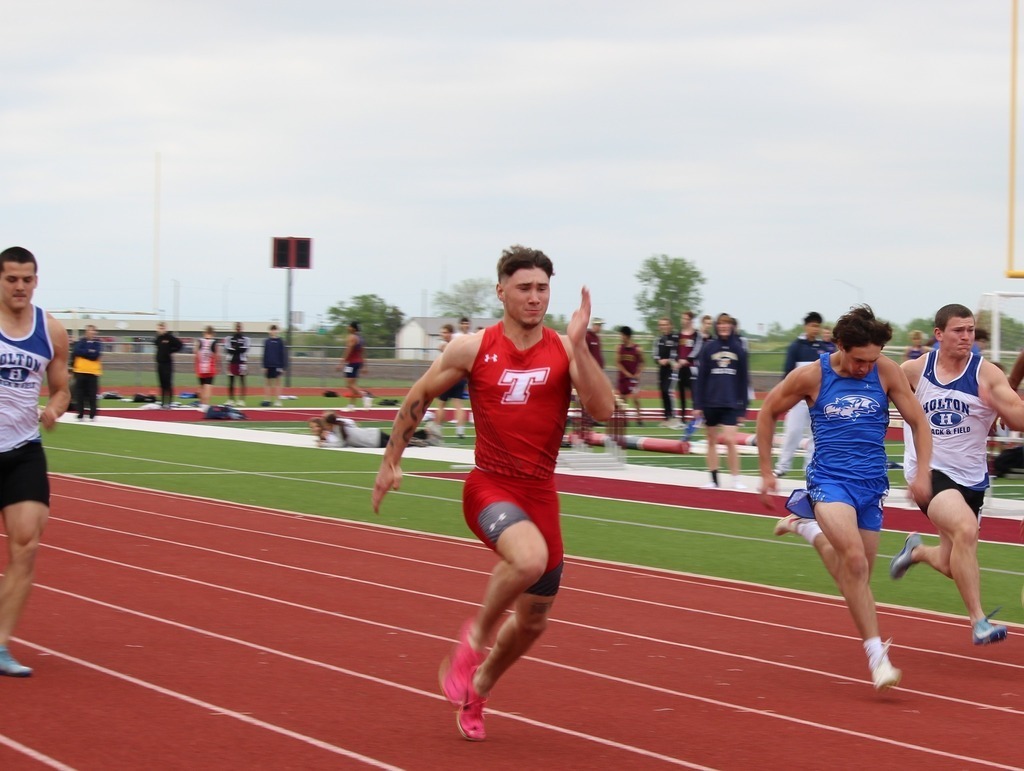 sprinter wearing red tank and shorts sprints down the track