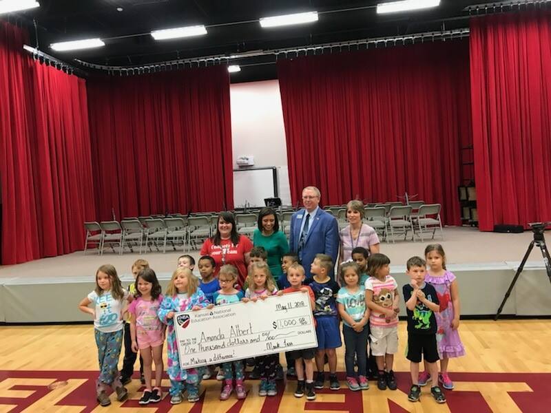 Amanda Albert stands with her class, holding a large check from KNEA for $1000