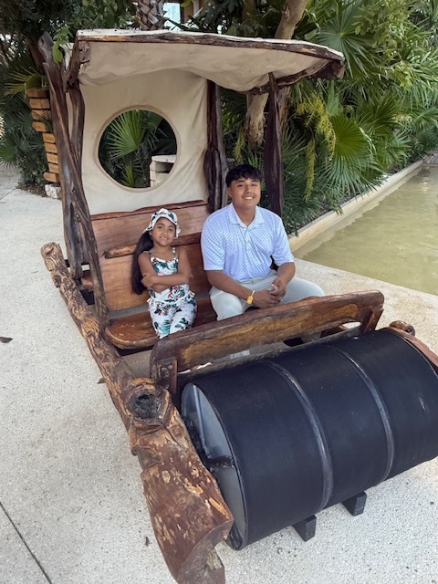 Ivan and Ana Franco sit in a flintstones style pedal car