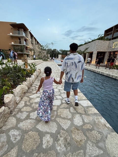 Ana and Ivan walk hand in hand down a stone walkway at a hotel