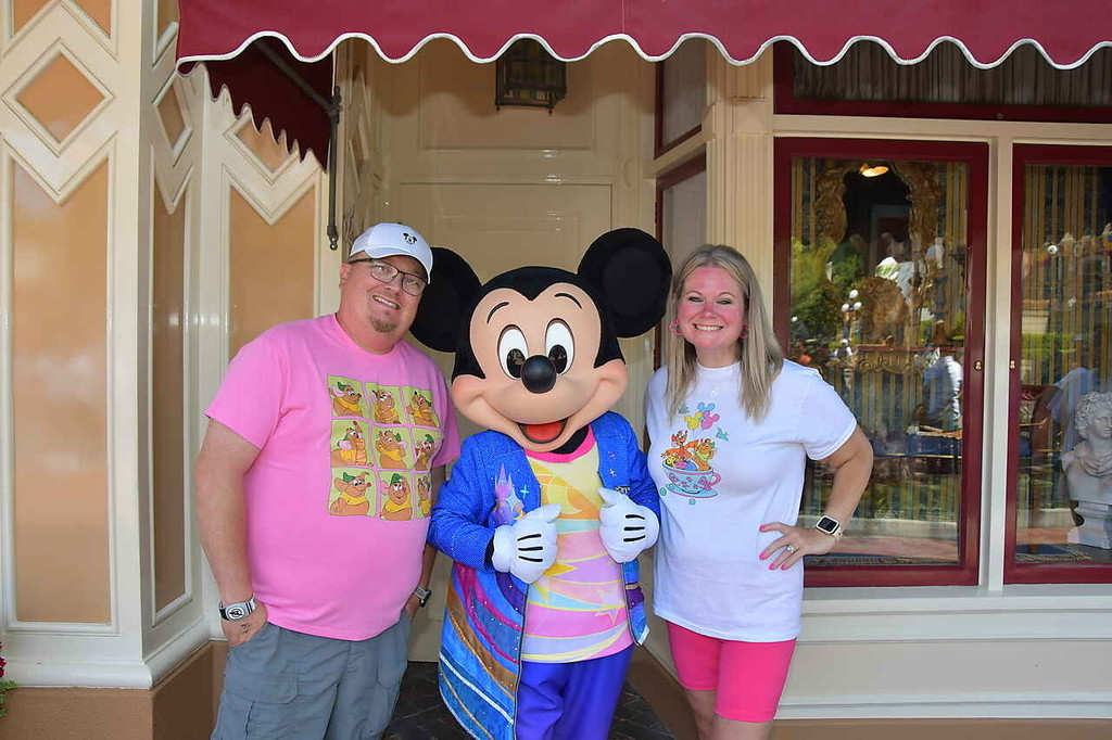 Josh and Amy Olsen standing on either side of Mickey Mouse