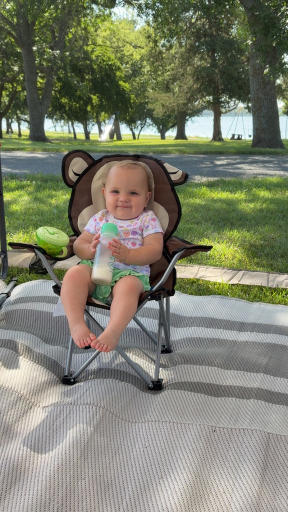 Baby Willow sitting in a miniature camp chair holding a bottle