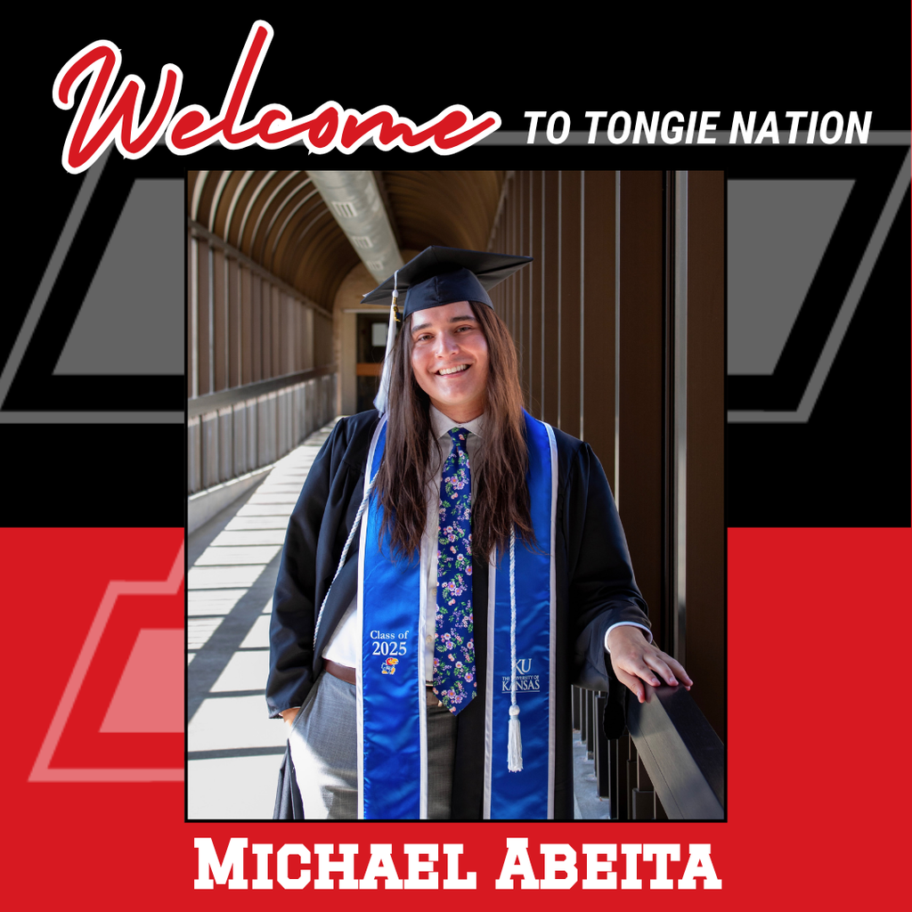 black and red background, Michael in the foreground wearing gray pants, white shirt, black graduation cap and gown, and blue KU graduation cords