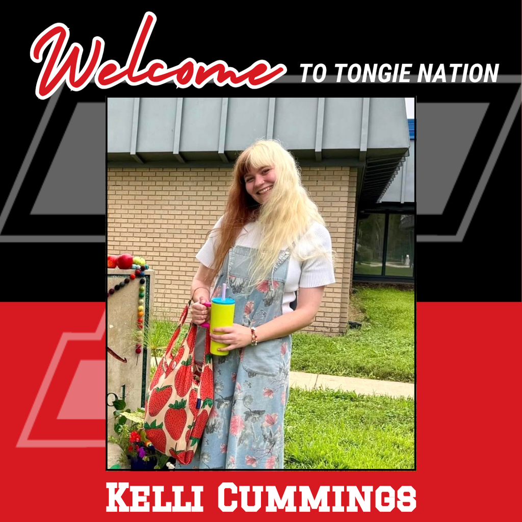 black and red background, Kelli wearing white shirt and blue and pink flowered jumper, holding a yellow water bottle in her hands and carrying a strawberry print tote bag on her arm