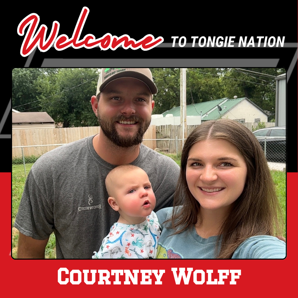 courtney wolff wearing a blue shirt, holding a baby; he r husband stands next to her in a gray shirt