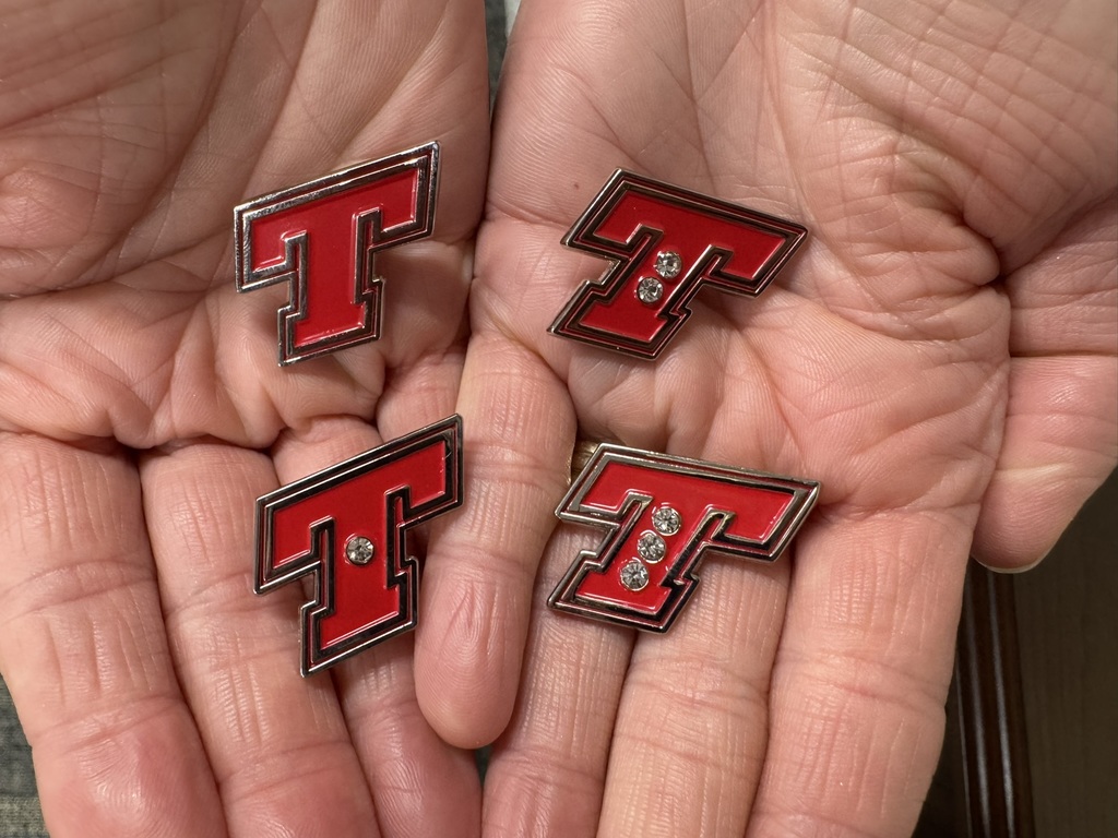 four red T pins in the palms of two hands