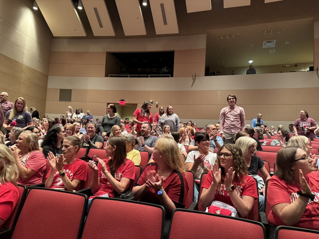 staff sitting in red chairs in an auditorium