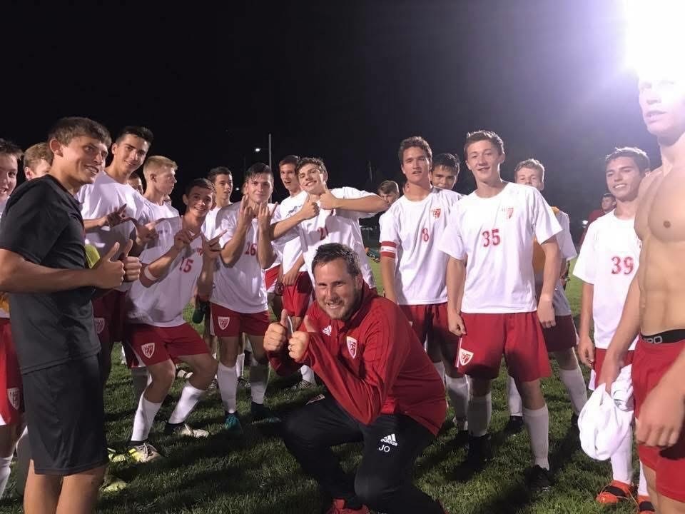 boys soccer team members wearing white jerseys and red shorts