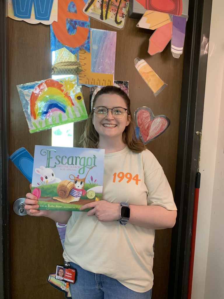 Art teacher in a 1994 shirt holding a a book called Escargot.