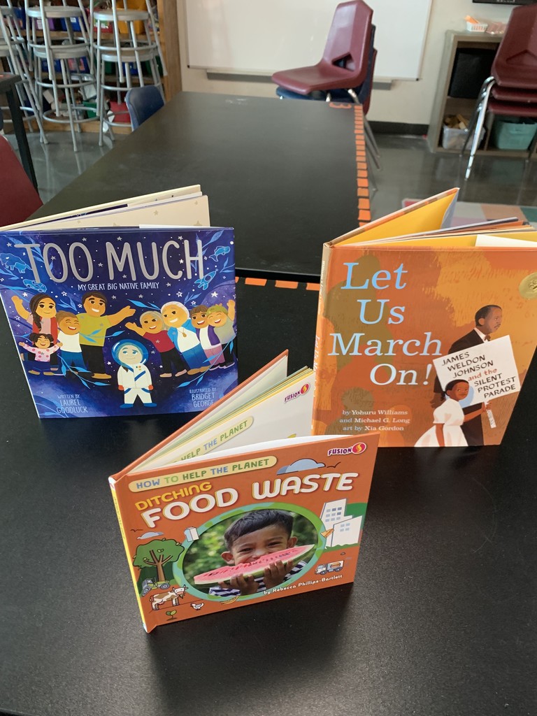 Three illustrated books on a table.  Too Much, Food Waste & Let Us March On.