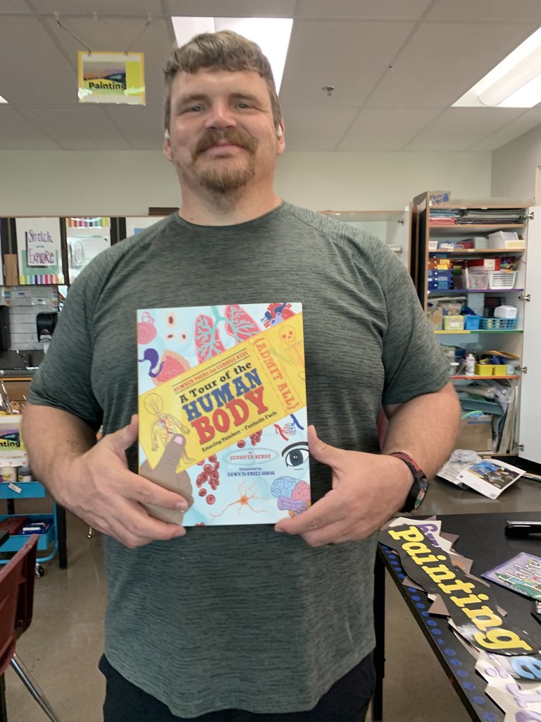 Male PE teacher with a book about the human body.