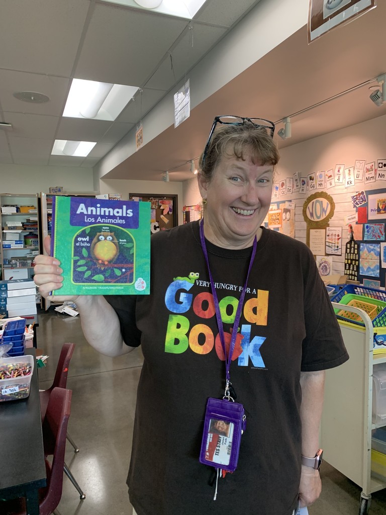 Title Reading Teacher in a black shirt that says "Good Book", holding a book about animals.