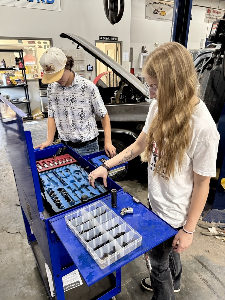 two students pulling tools out of a blue toolbox