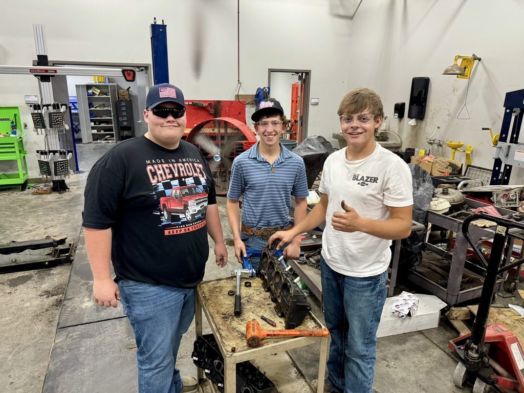 three male students working on an engine head