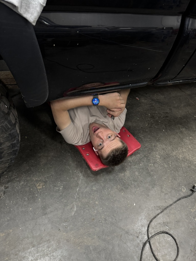 a student on a roller slides out from underneath a black truck