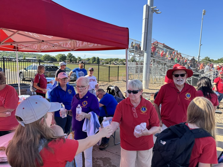 lions club members hand bottles of water to students and parents