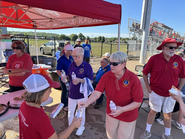 lions club members hand bottles of water to students and parents