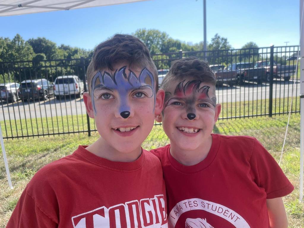 two boys wearing red t shirts, their faces are painted like wolves