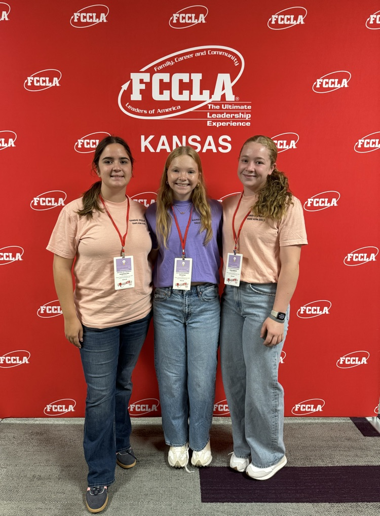 fccla members wearing jeans and branded t shirts, standing in front of a red FCCLA backdrop