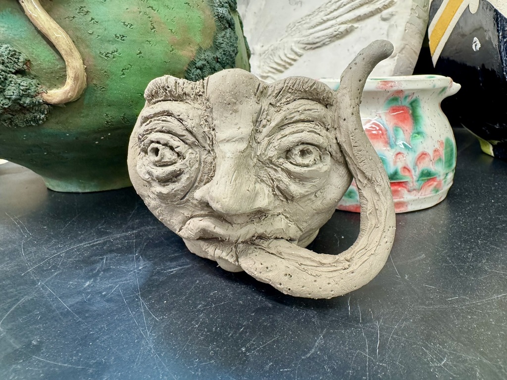 a clay face mug with a super long tongue