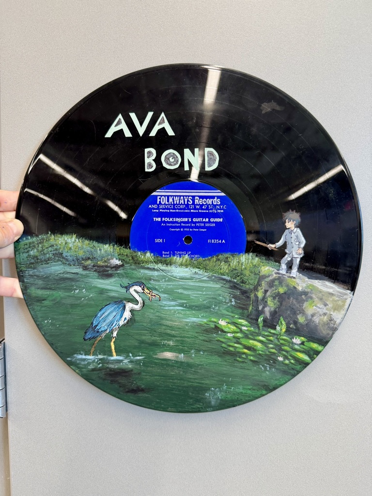 a vinyl record painted with a scene of a pond with a heron and a boy in pajamas