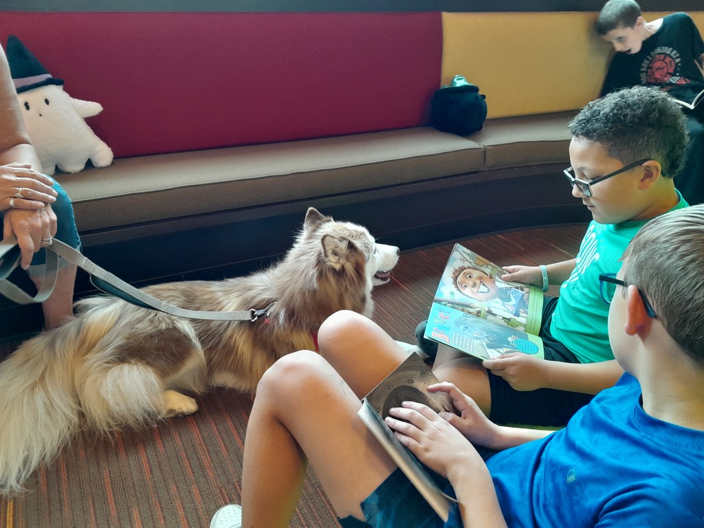 two fifth grade boys read to a brown dog