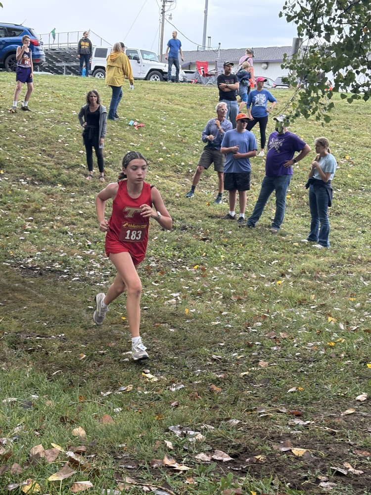 Amelia runs in a red uniform through a field.