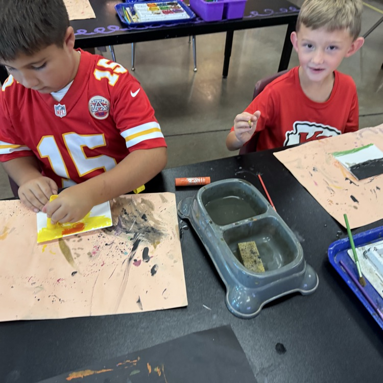 two students painting with tempera paints and tempera paint sticks