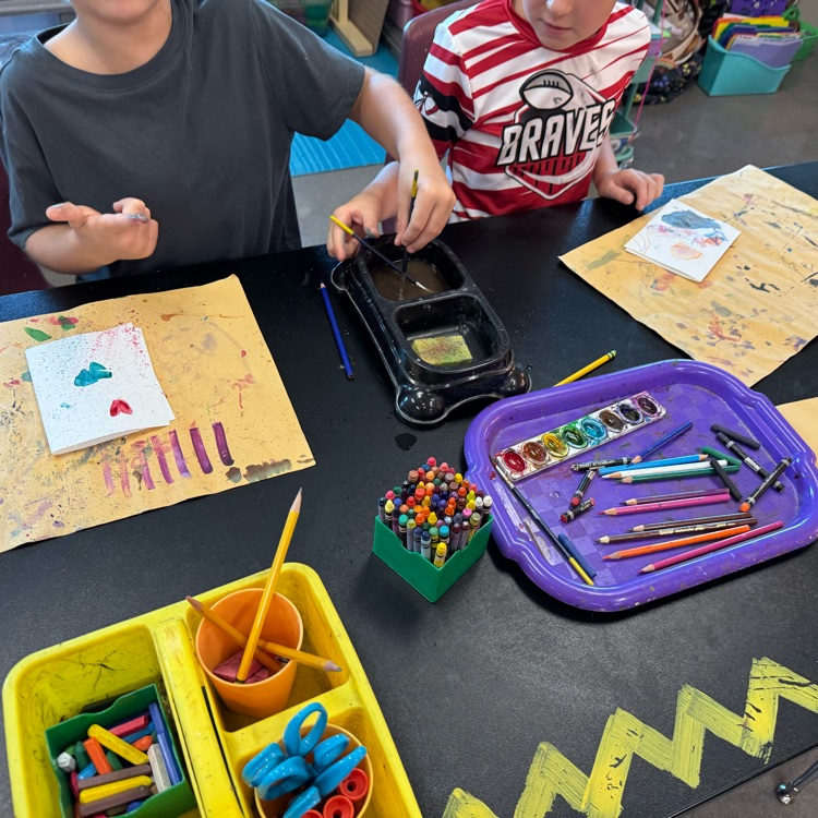 two students trying out controlled splatter paint using watercolors