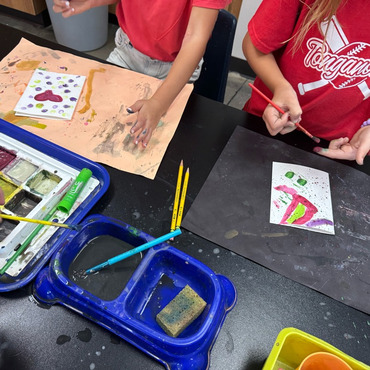 two students experimenting with tempera cakes and trying controlled splatter painting