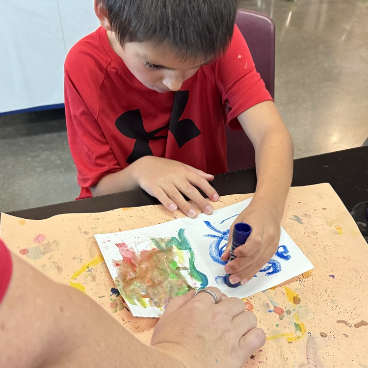 student concentrating on drawing numbers with the paint sticks