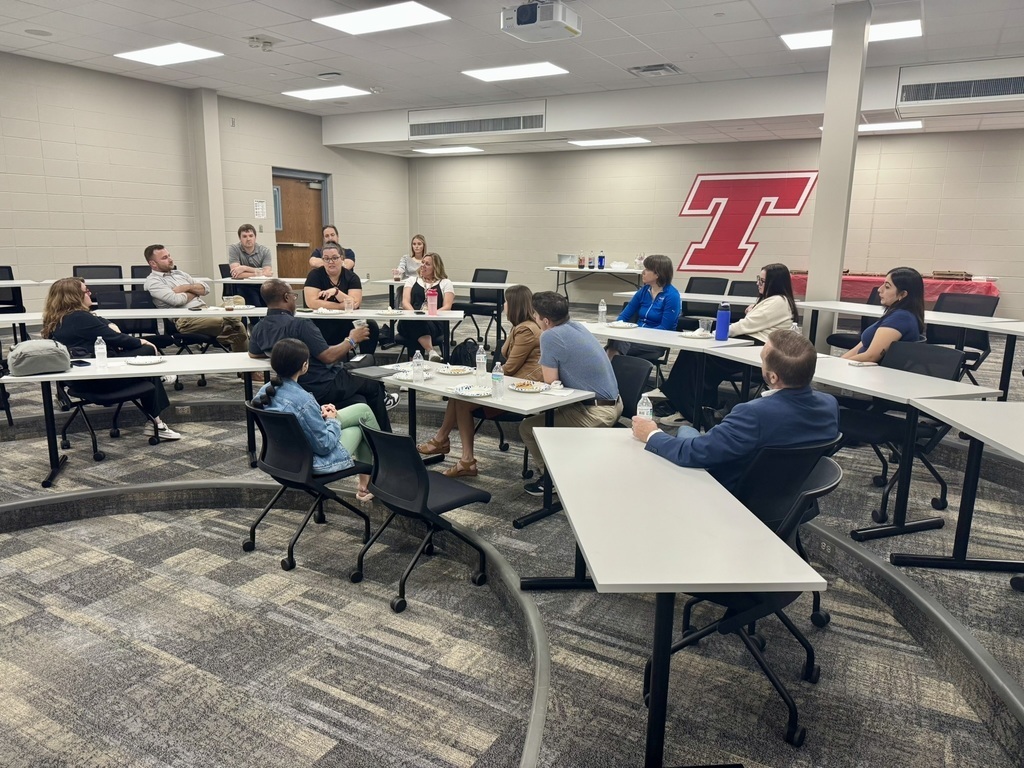 school PR pros wearing business casual attire sitting at gray rectangular tables
