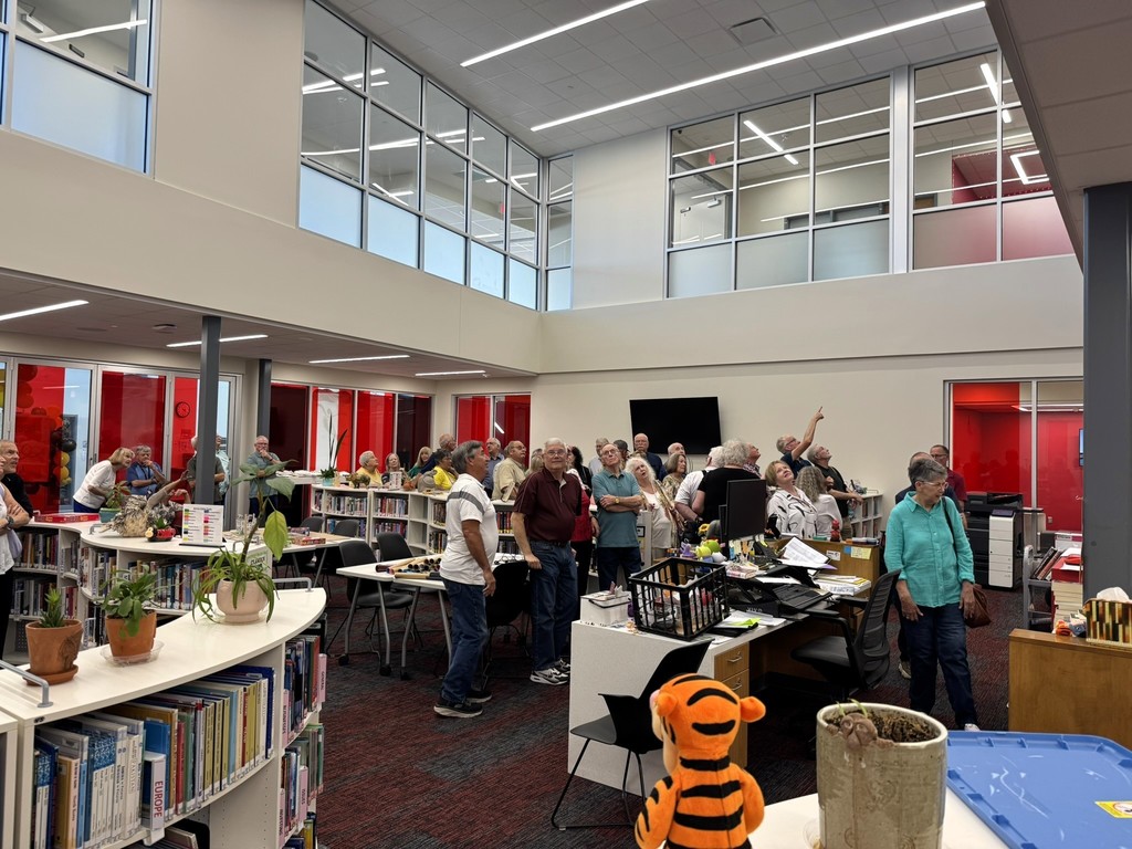 members gathered in the library looking up at the mural