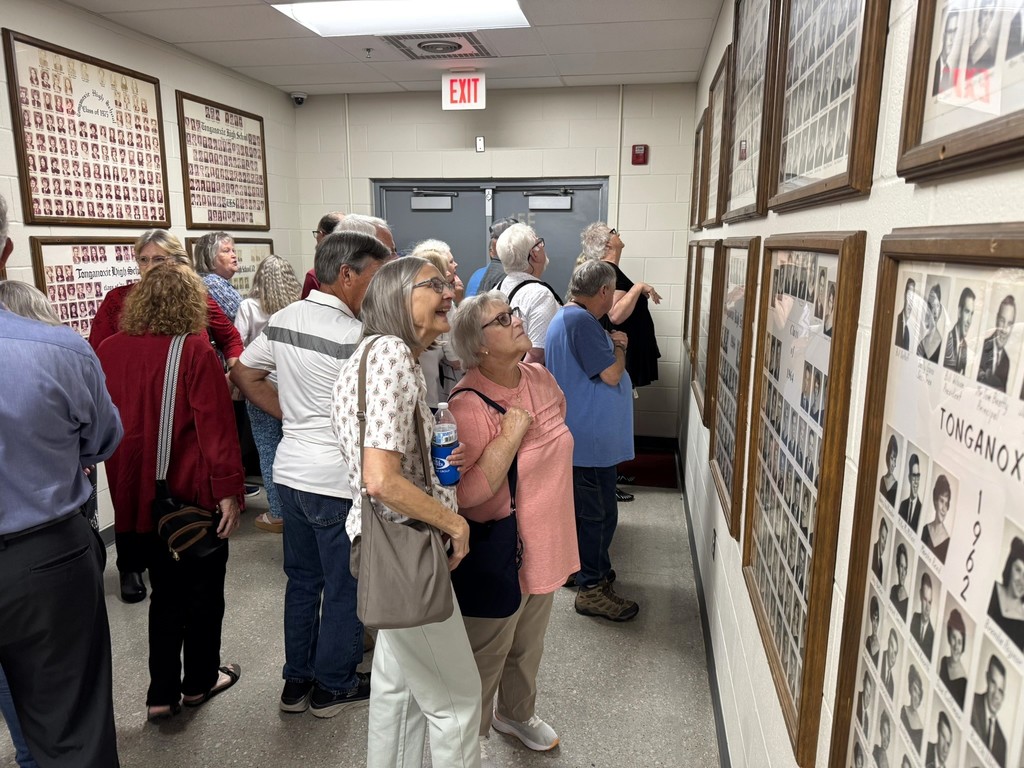 members gathered in chieftain hallway to look at black and white class photos 