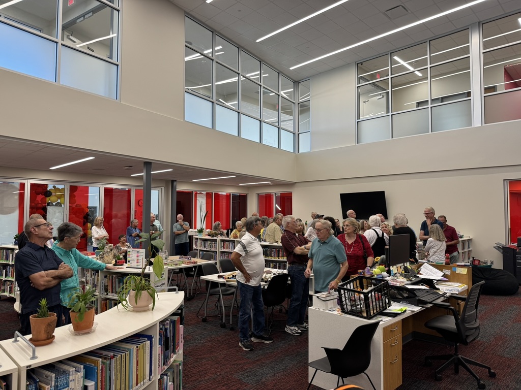 members gathered in the library looking up at the mural