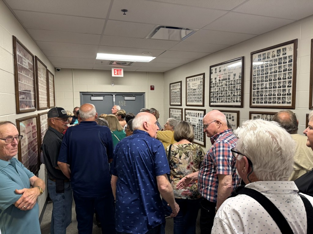 members gathered in chieftain hallway to look at black and white class photos 