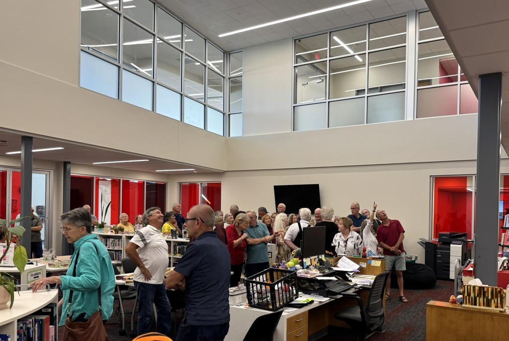 members gathered in the library looking up at the mural